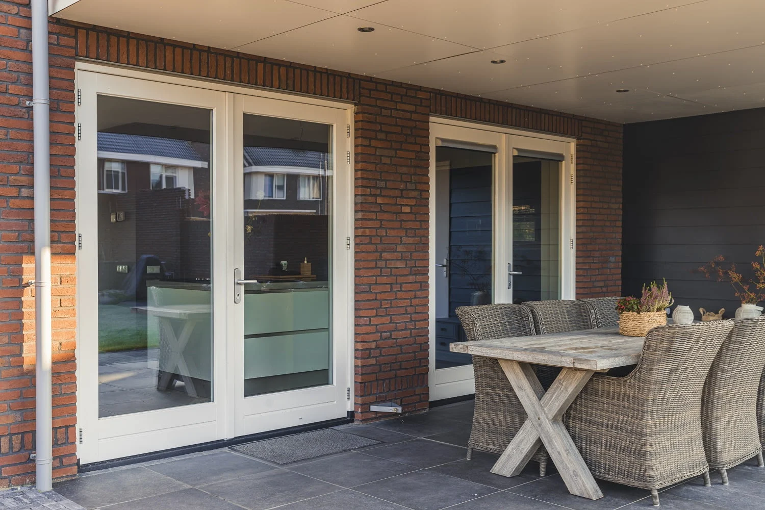 Witgelakte dubbele tuindeuren met grote glasvlakken in houten kozijn, geplaatst in een gevel onder een overkapping – Toelevering Online