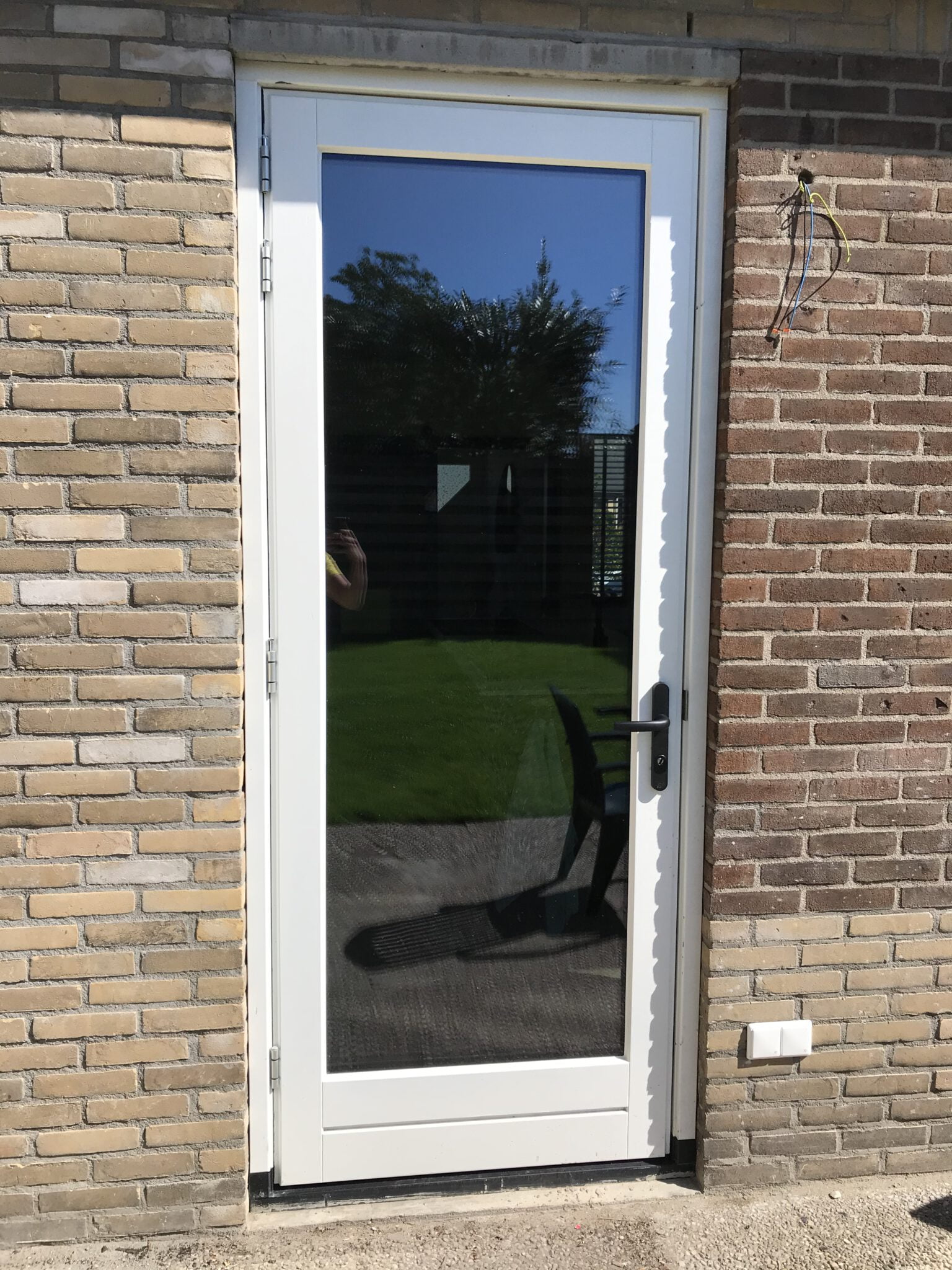Detail van een witte deur met glas en goed afgewerkte aansluiting tussen kozijn en gemetselde buitenmuur voor optimale afdichting en tochtwering – Toelevering Online